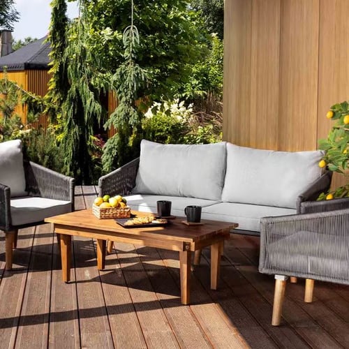 Gartenmöbel-Set von di volio mit grauen Polstern und Holztisch auf Holzterrasse umgeben von Pflanzen