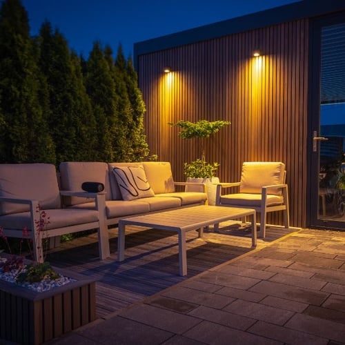 Moderne Terrassensitzgruppe mit warmen LED-Wandlampen am Abend