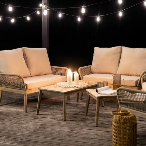  Gemütliche Terrassenlounge von di volio mit Polyrattansofa, Kerzenlicht und Lichterkette bei Nacht