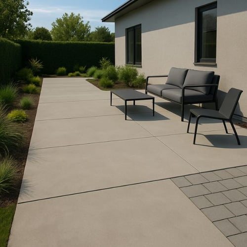 Schlichter Gartenweg mit großen Betonplatten und modernen Gartenmöbeln neben Hauswand