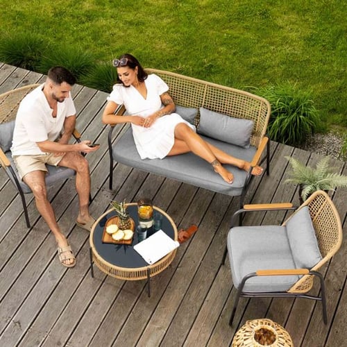 Gemütliche Gartensitzgruppe von di volio mit grauen Polstern und Rattanelementen auf Holzterrasse, zwei Personen entspannen.