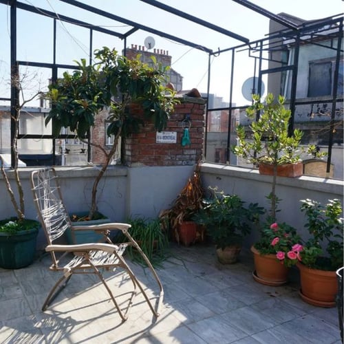 Kleine Dachterrasse mit Topfpflanzen und klappbarem Metall-Liegestuhl