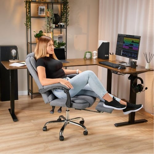 Frau im ergonomischen Bürostuhl am Eckschreibtisch im gemütlichen Homeoffice