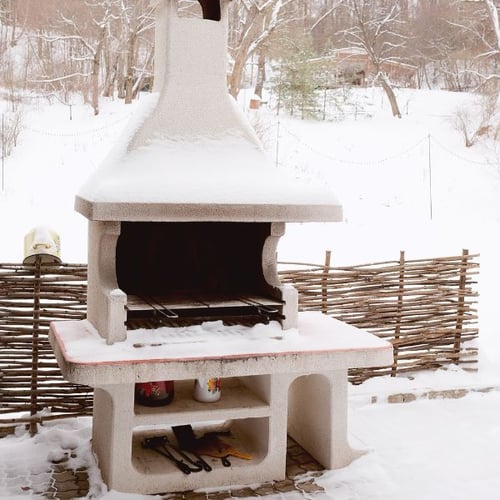 Gemauerter Grill im Winter mit Schnee bedeckt.