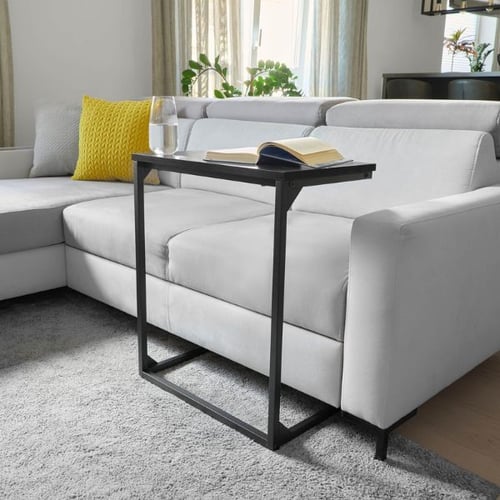 Schwarzer C-förmiger Beistelltisch am weißen Sofa im Wohnzimmer