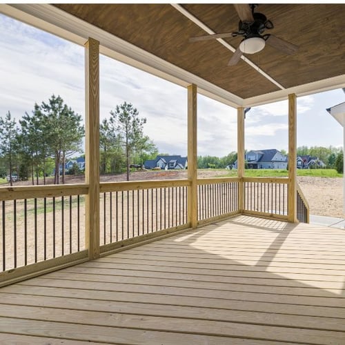 Überdachte Holzveranda mit Geländer und Blick in den Garten