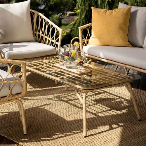 Rattan-Sitzgruppe mit Glastisch von di volio und Kissen auf sonniger Loggia