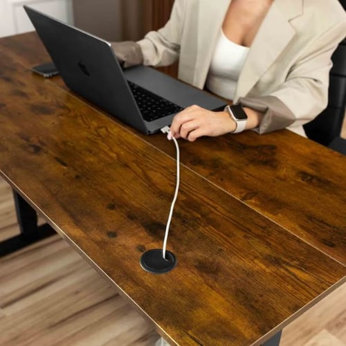 Frau arbeitet am Laptop an einem höhenverstellbaren Schreibtisch mit Kabeldurchlass in rustikaler Holzoptik