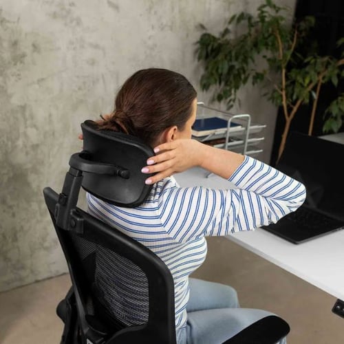 Frau stellt die Nackenstütze eines ergonomischen Bürostuhls im Büro ein