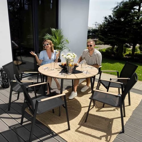 Runde Gartensitzgruppe mit sechs Stühlen und Gartentisch von di volio, genutzt von zwei Personen beim Essen im Freien