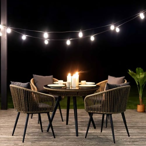 Beleuchtete Sitzgruppe auf Terrasse mit Kerzen und Lichterkette im Winter