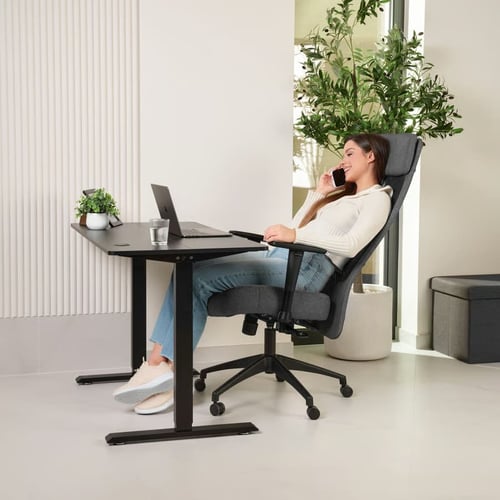 Kobieta rozmawiająca przez telefon i pracująca zdalnie w domowym biurze, siedząca na wygodnym, regulowanym krześle - inspiracja, jakie krzesło do home office wybrać dla komfortu i relaksu.