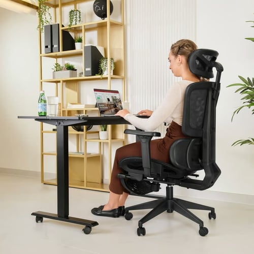 Kobieta korzystająca z laptopa, siedząca w ergonomicznym fotelu z podparciem lędźwiowym i siatkowym oparciem – doskonały przykład, jaki fotel ergonomiczny do 1000 zł zapewnia komfort pracy i wsparcie pleców.