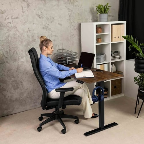 Kobieta pracująca w home office przy biurku, siedząca na ergonomicznym fotelu biurowym z wysokim oparciem - przykład, jakie krzesło do home office zapewnia wygodę i wsparcie dla kręgosłupa.