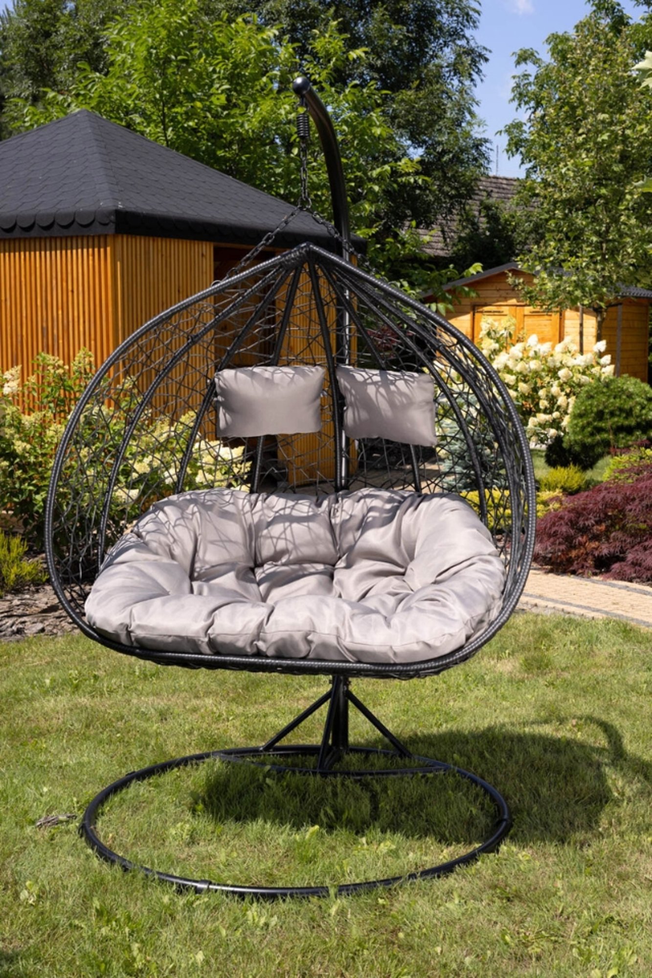 huśtawka kokon foggio czarna stojąca w ogrodzie